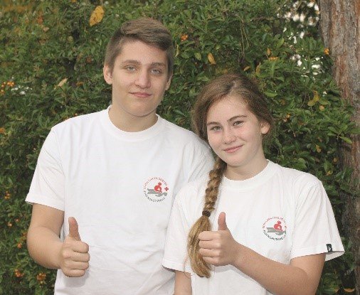 Eine Schulsanitäterin und ein Schulsanitäter finden den Schulsanitätsdienst gut und zeigen den Daumen nach oben.